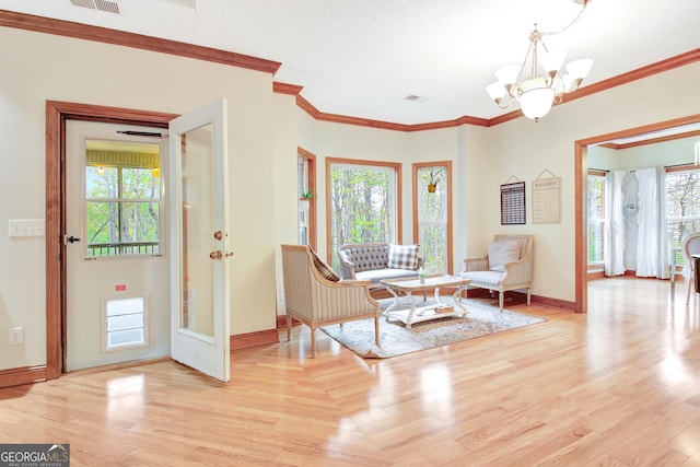 living area with a wealth of natural light, a chandelier, ornamental molding, and baseboards