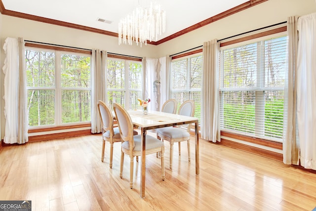 dining area featuring ornamental molding, an inviting chandelier, visible vents, and light wood-style floors