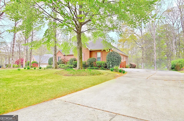view of front of property with concrete driveway, a front yard, and brick siding
