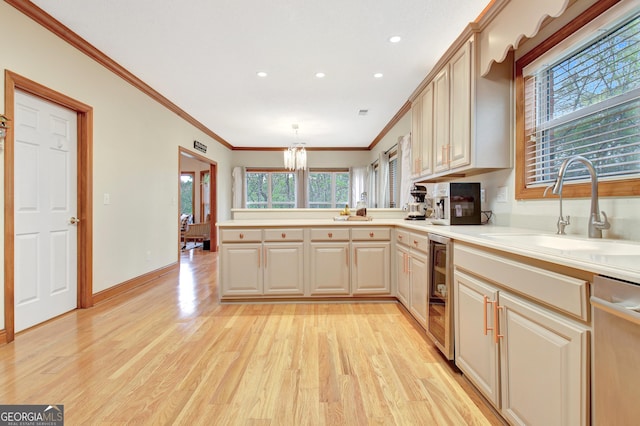 kitchen featuring beverage cooler, light wood-style flooring, dishwasher, a sink, and a peninsula