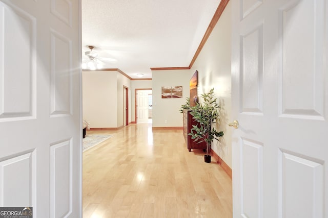 hallway featuring ornamental molding, light wood-style flooring, and baseboards