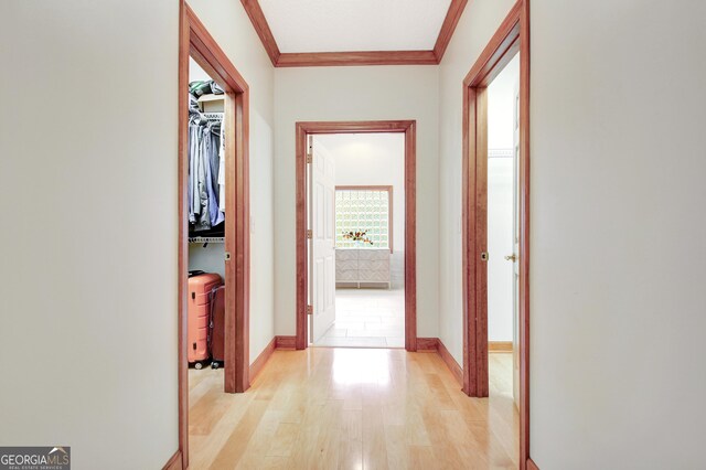 hallway with crown molding, light wood-style flooring, and baseboards