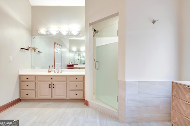 bathroom with vanity, a shower stall, and baseboards