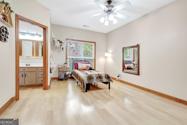 bedroom featuring light wood finished floors, a sink, baseboards, and visible vents