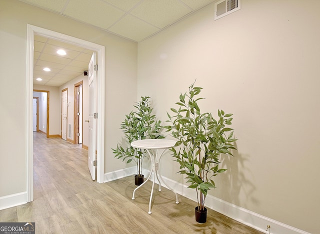 hall with baseboards, recessed lighting, wood finished floors, and a paneled ceiling