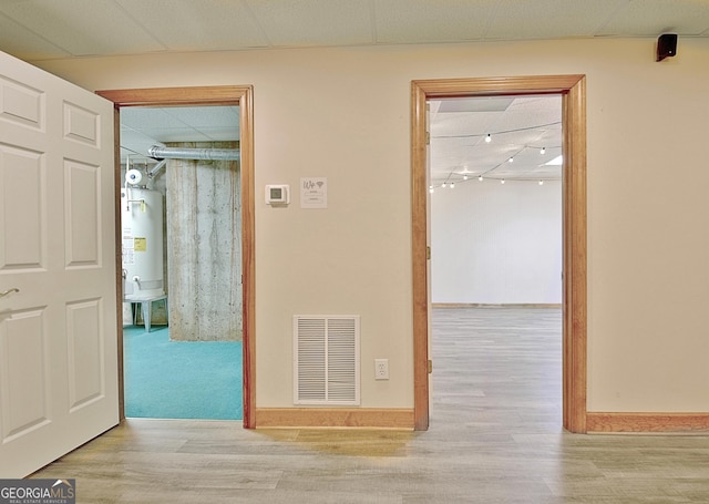 corridor with visible vents, wood finished floors, and water heater