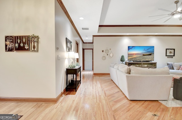 living room featuring ceiling fan, crown molding, light wood finished floors, and baseboards