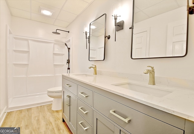 full bathroom featuring wood finished floors, a drop ceiling, toilet, and a sink