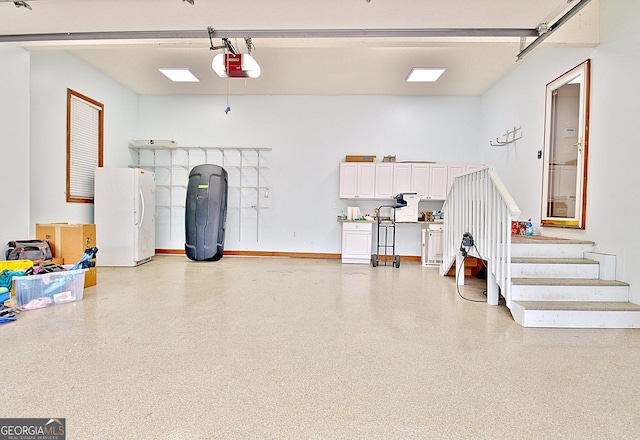 garage featuring freestanding refrigerator, a garage door opener, and baseboards