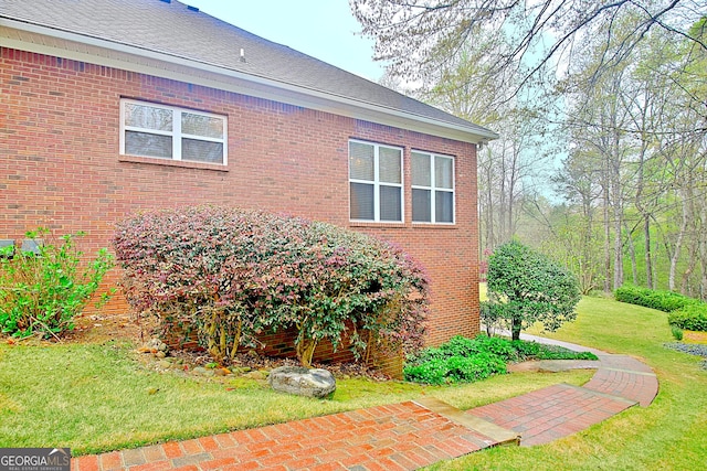 view of side of property with a yard and brick siding