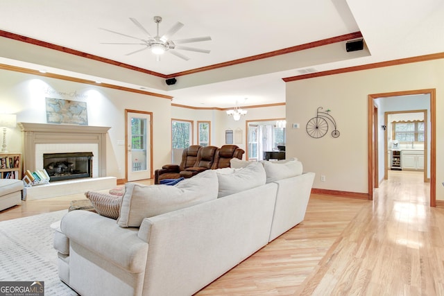 living room featuring beverage cooler, baseboards, light wood finished floors, a fireplace, and ceiling fan with notable chandelier
