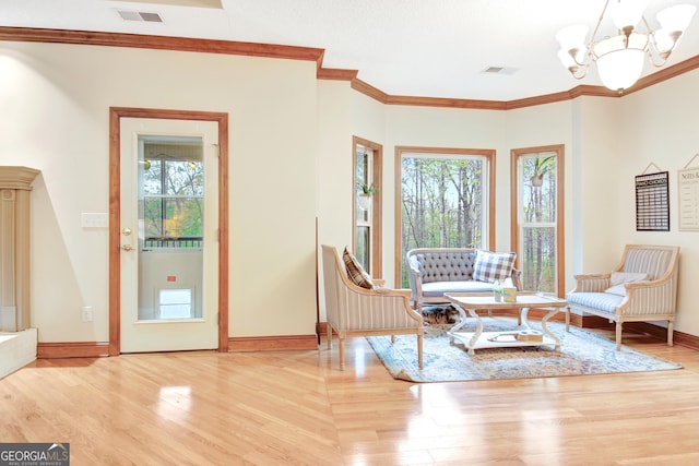 living area with visible vents, wood finished floors, an inviting chandelier, and plenty of natural light