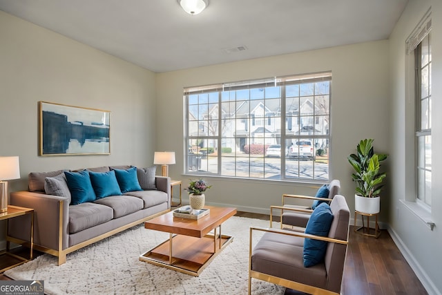 living room with baseboards, visible vents, and wood finished floors
