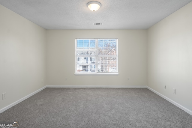 carpeted spare room featuring a textured ceiling, baseboards, and visible vents