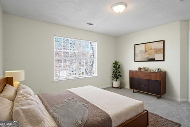 bedroom with light carpet, baseboards, visible vents, and a textured ceiling