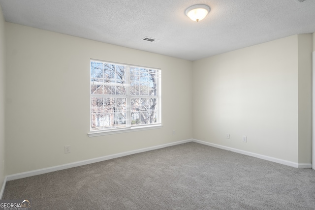 spare room with baseboards, visible vents, carpet, and a textured ceiling