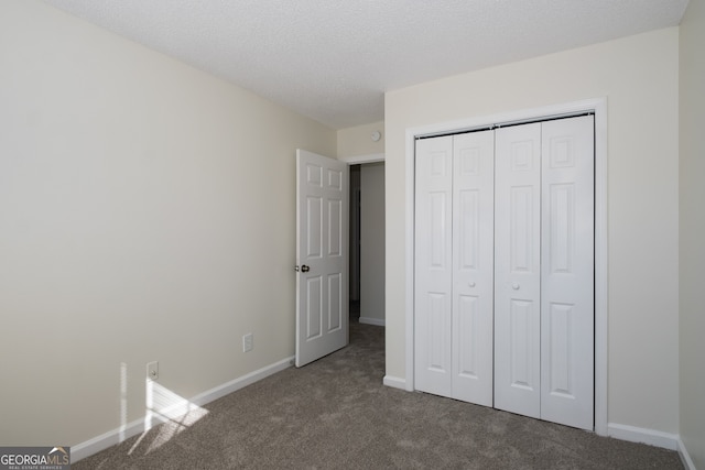 unfurnished bedroom featuring baseboards, a textured ceiling, a closet, and carpet