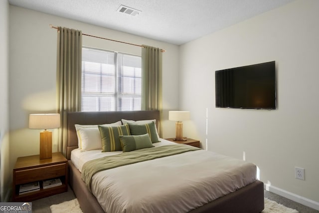 bedroom featuring carpet floors, a textured ceiling, baseboards, and visible vents