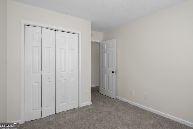 unfurnished bedroom with carpet floors, baseboards, a closet, and a textured ceiling