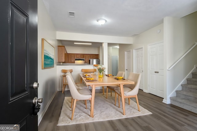 dining area with dark wood finished floors, baseboards, stairs, and visible vents