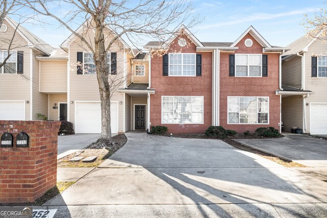 view of property featuring brick siding, driveway, and an attached garage