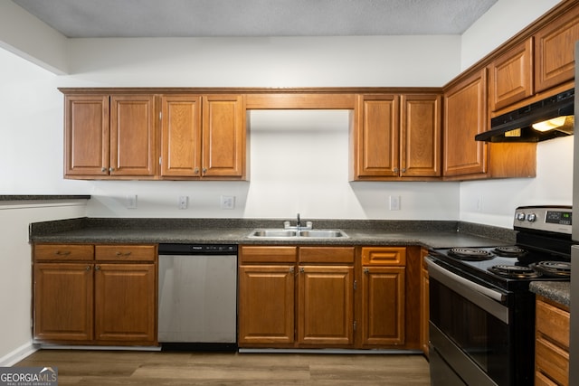 kitchen featuring under cabinet range hood, a sink, dark countertops, range with electric stovetop, and dishwasher