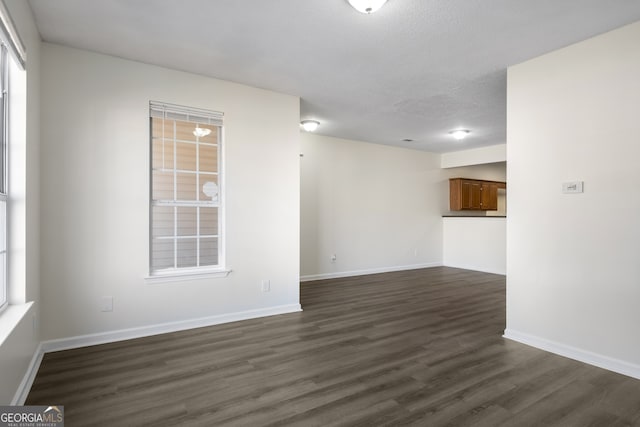 spare room featuring dark wood finished floors, baseboards, and a textured ceiling