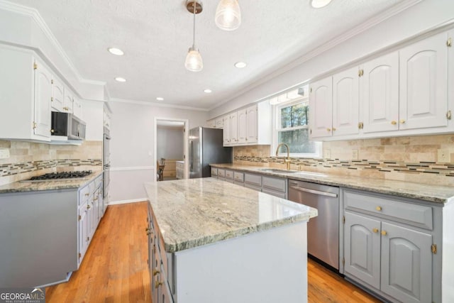 kitchen with stainless steel appliances, a sink, light wood-type flooring, gray cabinets, and a center island
