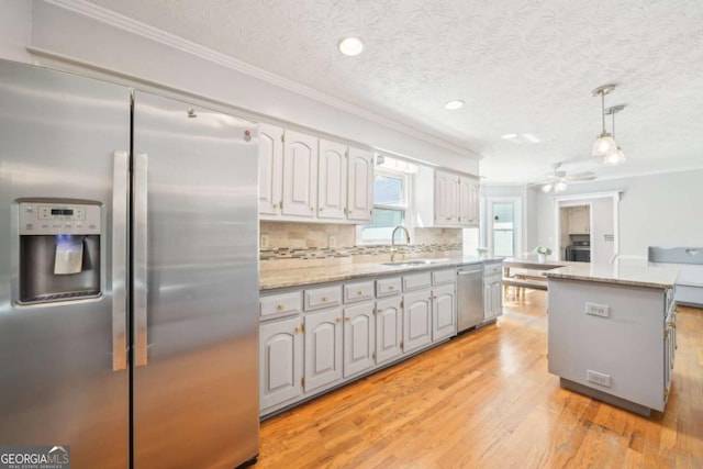 kitchen featuring tasteful backsplash, crown molding, stainless steel appliances, a textured ceiling, and light wood-style flooring