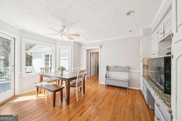 dining area with a textured ceiling, crown molding, a ceiling fan, and light wood finished floors