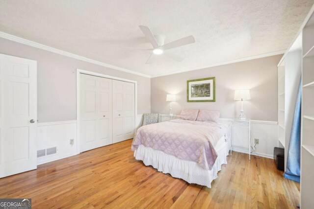 bedroom featuring visible vents, crown molding, wood finished floors, and a closet