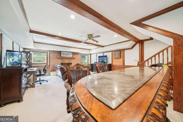 carpeted dining space with a fireplace, a tray ceiling, a ceiling fan, and ornamental molding