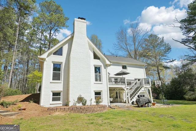 rear view of house featuring stairway, a deck, brick siding, a yard, and a chimney