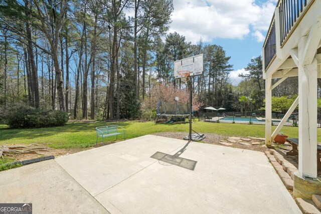 view of patio with an outdoor pool, fence, and a trampoline