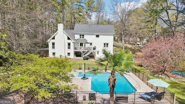 rear view of property with a patio area, a chimney, fence, and a fenced in pool