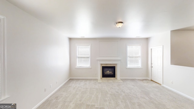unfurnished living room featuring baseboards, a tile fireplace, and light carpet