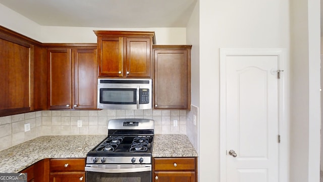 kitchen with stainless steel appliances, tasteful backsplash, and light stone counters