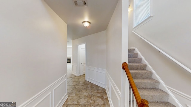 stairs featuring a wainscoted wall, a decorative wall, and visible vents