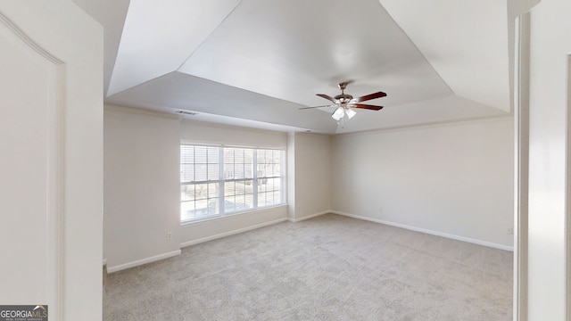 carpeted spare room featuring a ceiling fan, a tray ceiling, baseboards, and visible vents