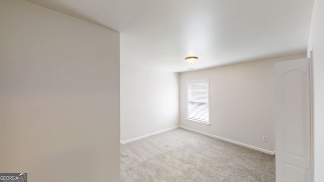 empty room featuring baseboards and light colored carpet