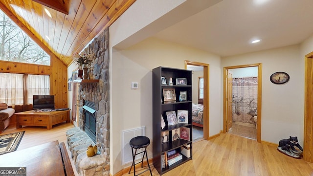 living room with visible vents, baseboards, wood finished floors, and a stone fireplace