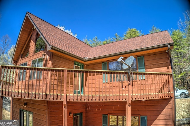 back of house with a shingled roof and a balcony