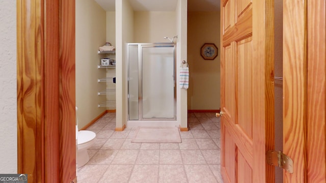 bathroom featuring baseboards, tile patterned flooring, a stall shower, and toilet