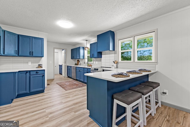 5697 Yatesville Hwy, Yatesville, GA 31097 - kitchen with wall chimney exhaust hood, a textured ceiling, stainless steel appliances, light wood-style flooring, and blue cabinets