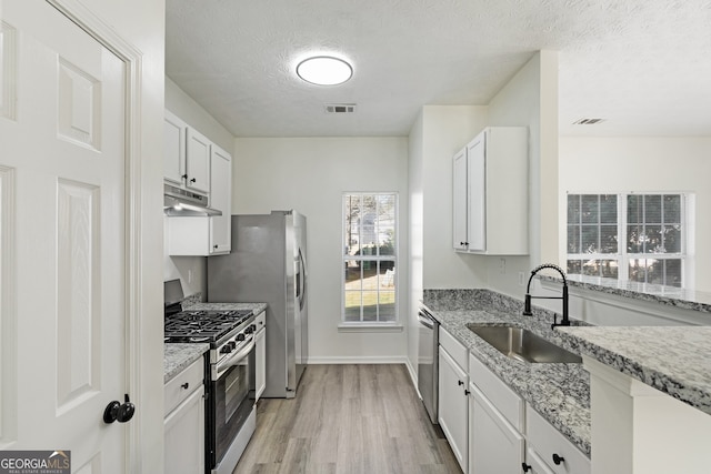 4917 Walden Lake Sq, Decatur, GA 30035 - kitchen with appliances with stainless steel finishes, light wood-style floors, a textured ceiling, light stone countertops, and under cabinet range hood