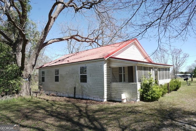 319 Isabella St, Abbeville, GA 31001 - view of side of home featuring a sunroom, a metal roof, and a lawn