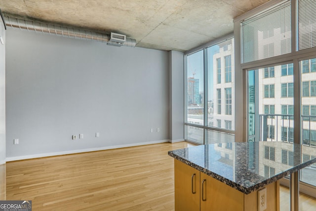 943 Peachtree St NE Unit 1003, Atlanta, GA 30309 - kitchen with healthy amount of natural light, light wood finished floors, a wall of windows, dark stone counters, and a center island