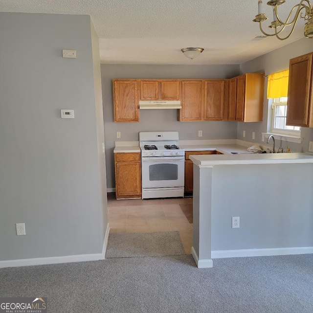 kitchen with light countertops, under cabinet range hood, white gas range, and a textured ceiling