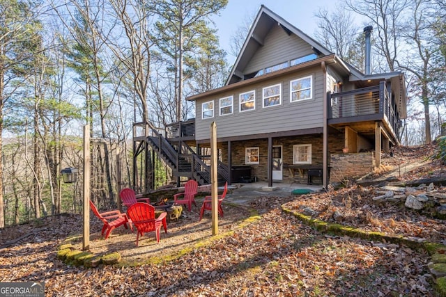 back of house featuring stone siding, a deck, stairs, and a patio area