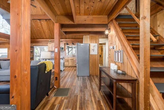 interior space featuring wood ceiling, wooden walls, wood finished floors, beamed ceiling, and visible vents